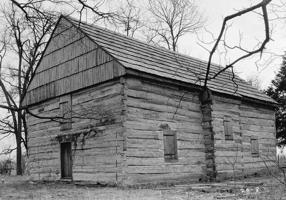 The Cane Ridge Meeting House, a one-room log building with a shingled roof, photographed before the protective stone superstructure was built around it.